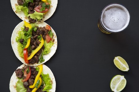 Mexican tacos with beef and vegetables, beer and lime on a black background, top view. Copy space. Flat lay.の写真素材