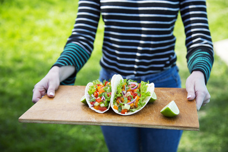 Woman holding a rustic board with Mexican tacos. Closeup.の写真素材