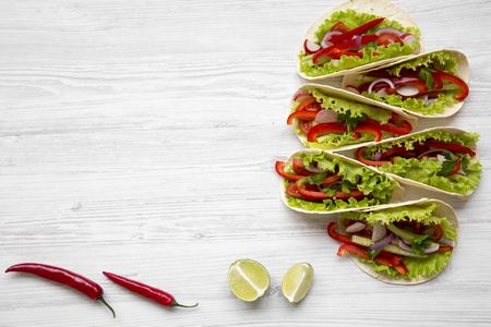 From above corn tortillas with redish, cucumber, onion, parsley, pepper  and lettuce on white wooden background. Copy space. Top view.の写真素材