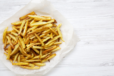 French fries on white wooden background with copy space, top view, close up. Flat lay. 
