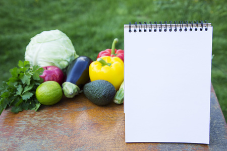 Healthy food concept. Notebook and collection of different fruits and vegetables on wooden rustic table. Side view.の写真素材
