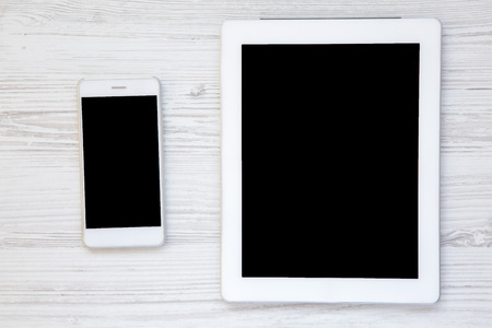 Smartphone and tablet with a blank screen on a white wooden background, top viewの写真素材