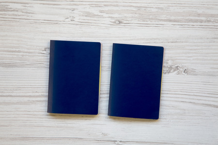Two blank blue passports on white wooden background
