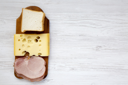 Set of ingredients for making sandwich: toast bread, cheese and bacon on white wooden background. Copy space. Top view.の写真素材