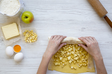 Young girl is cooking apple pie or strudel on white wooden background. Top view. From above. Copy space.の写真素材