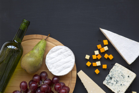 Tasting cheese with fruits and wine on dark background. Food for romantic. Copy space. Flat lay. From above, top view.の写真素材