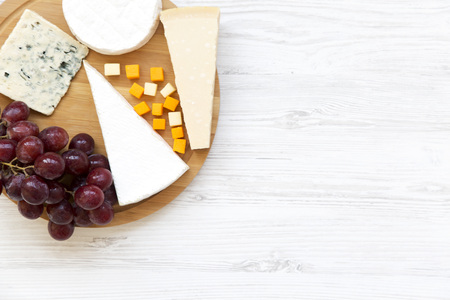 Tasting cheese with grapes on white wooden background. Food for wine, top view. Space for text. Flat lay. From above.の写真素材