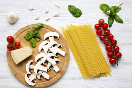 Round wooden board with ingredients for cooking pasta on a white wooden background. Top view. Flat lay. From above.の写真素材