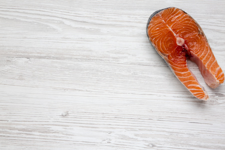 Raw salmon steak on white wooden background, top view. Flat lay. From above. Copy space.