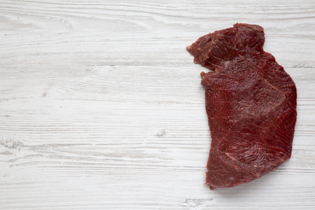 Uncooked raw beef meat on white wooden background, top view. Flat lay. From above. Copy space.の写真素材