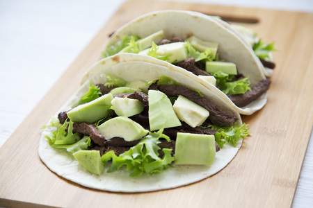 Mexican food. Carnitas street tacos in corn tortillas on wooden board. Side view.の写真素材