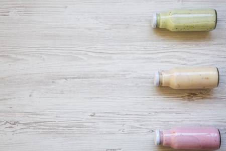 Fruit smoothies of different colors in glass jars on white wooden background. Top view, from above. Copy space. の写真素材