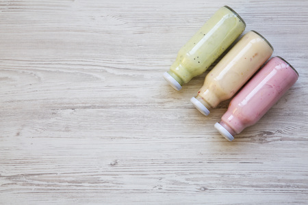 Fruit smoothies of different tastes in glass jars on white wooden background. Top view, from above. Copy space. の写真素材