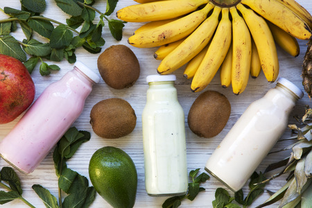 Fruit smoothies of different tastes in glass jars with ingredients on white wooden background. Top view, from above. Flat lay.の写真素材