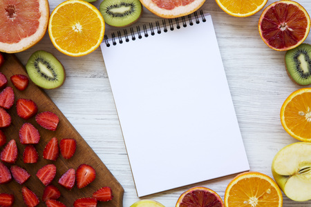 Top view, colorful fruits with notebook on a white wooden background. From above. Flat lay.の写真素材