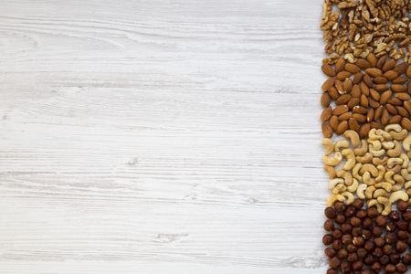 Assortment of nuts on white wooden background. Cashew, hazelnuts, walnuts, almonds. Top view, flat...