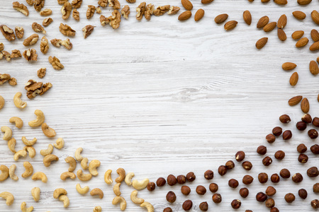 Different nuts on white wooden background. Cashew, hazelnuts, walnuts, almonds. Top view, flat lay....