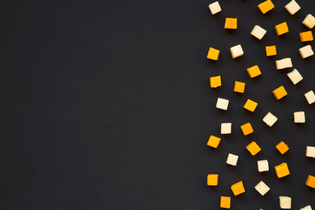 Mimolette and edam cheese on dark background with copy space, top view. Flat lay.