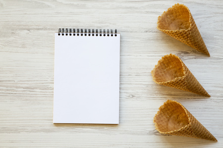 Top view, waffle sweet cones with notebook on a white wooden background. From above. Copy space.の写真素材