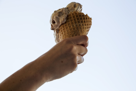 Woman's hand held caramel ice cream to summer sky の写真素材