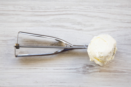 Vanilla ice cream in ice cream scoop on white wooden background, top view.の写真素材