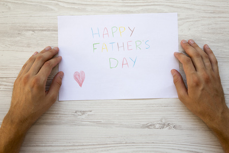 Happy Father's Day inscription with male hands on white wooden background.の写真素材
