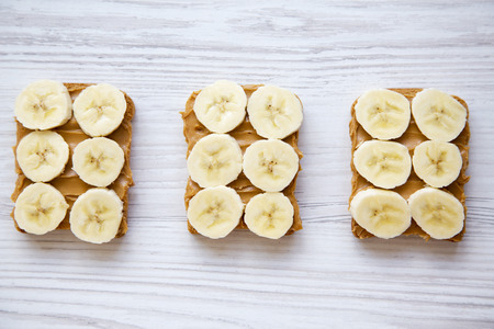 Vegan toasts with peanut butter and banana on a white wooden background, from above.の写真素材