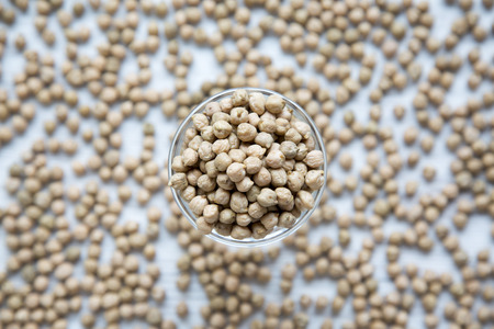 Bowl of dried chickpeas over white surface, top view. From above.の写真素材