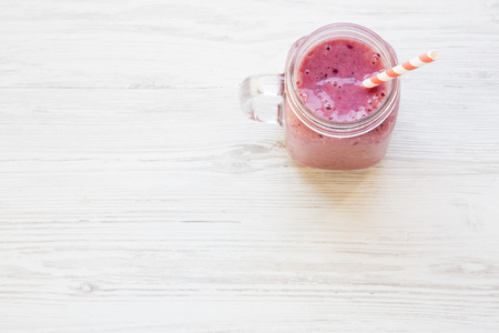 Freshly blended smoothie made of blackcurrant, banana, almond milk in glass jar. White wooden background. Copy space.の写真素材