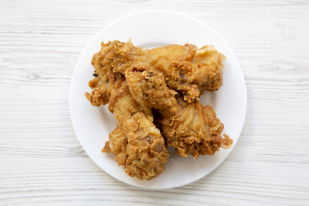 Fried chicken legs on a white plate over white wooden background, close-up. Top view, from above.の写真素材