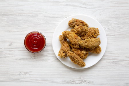 Top view, chicken wings on a round white plate with red pepper sauce over white wooden surface. From above, flat lay.の写真素材