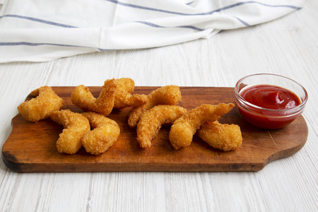 Fried shrimps tempura with sauce on wooden board over white wooden background, side view. Close-up.の写真素材