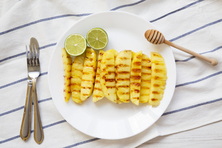 Grilled pineapple wedges with lime on white plate, top view. Summer food. From above, overhead, flat lay.の写真素材