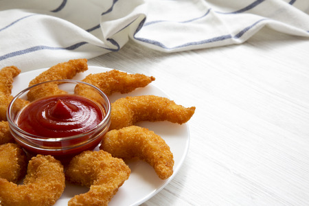 Fried shrimps tempura with sauce on white plate over white wooden surface, side view. Closeup. Copy...