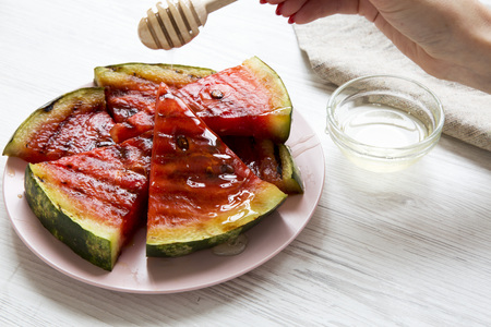 Slices of grilled watermelon with honey on a white wooden background, side view.の写真素材