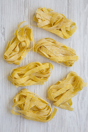 Uncooked pasta pappardelle on a white wooden table, top view. Overhead, flat lay.の写真素材