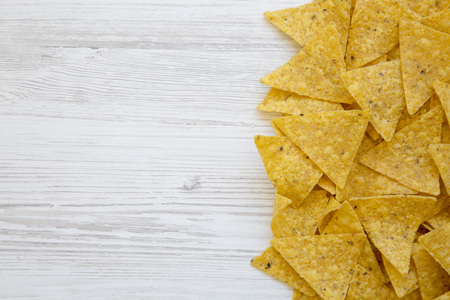 Tortilla chips on white wooden table, top view. Mexican food. Copy space.