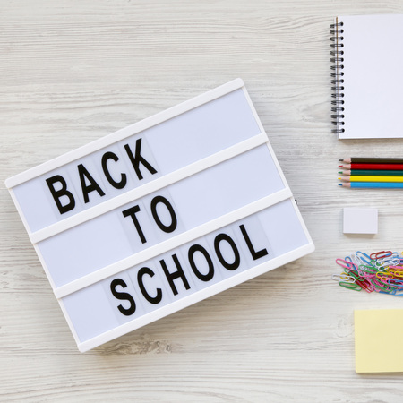 'Back to school' word on modern board, accessories for study over white wooden desk, view from above. Top view, flat lay, overhead.の写真素材
