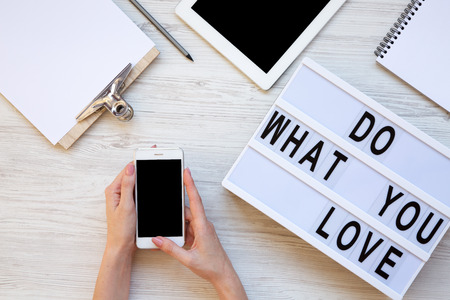 Work space with tablet, female hands, smartphone, clipboard and 'Do what you love' word on modern...