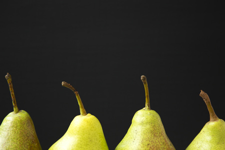 Fresh pears against black background, side view. Close-up. Organic fruits. Copy space.