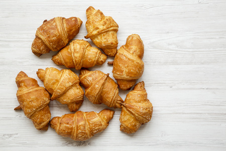 Freshly baked golden croissants on white wooden table, top view. Copy space.の写真素材