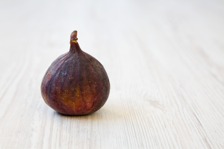 Fresh fig on a white wooden table, side view. Close-up. Copy space.