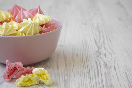 Mini meringues in a pink bowl over white wooden background, side view. Closeup. Copy space.の写真素材
