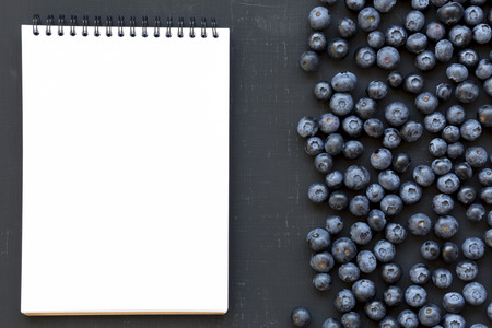 Ripe blueberries with notepad over dark background, from above. Summer berry. Flat lay, top view, overhead.の写真素材