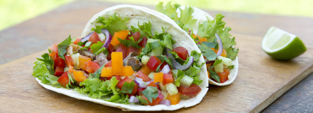 Mexican street pork tacos on wooden rustic board on wooden table, side view. Close-up.の写真素材
