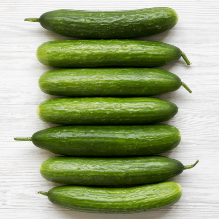 Flat lay of raw organic green cucumbers on white wooden surface. Top view, from above, overhead. Close-up.の写真素材