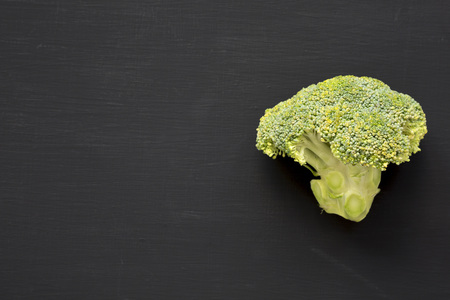 Raw broccoli on black background, top view. Flat lay, from above. Copy space.