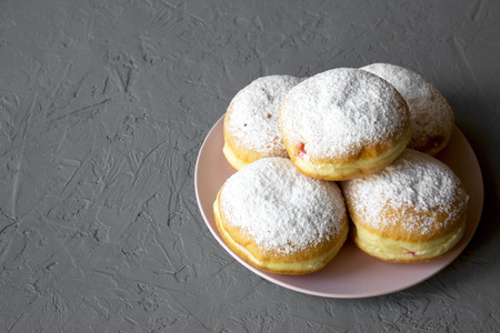 Homemade sweet donuts with powdered sugar on pink plate over concrete background, side view. Copy space.の写真素材