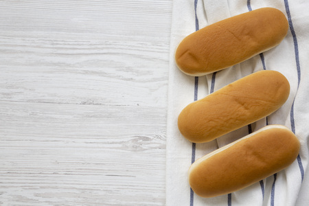 Hot dog buns on wooden board on white wooden background, top view. Flat lay, from above, overhead. Copy space.の写真素材