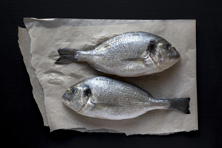 Fresh dorado fish on baking paper over dark background, overhead view. Flat lay, from above, top view.の写真素材